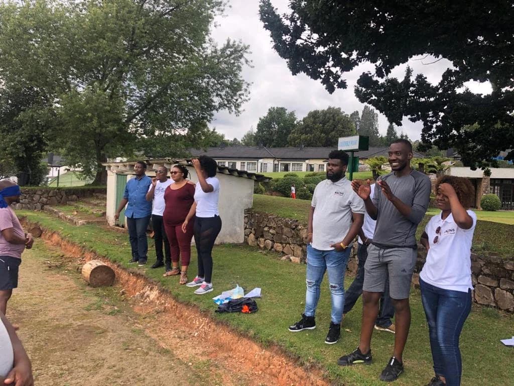 Grupo em atividade de comunicação e confiança, ao ar livre, durante a sessão de team building